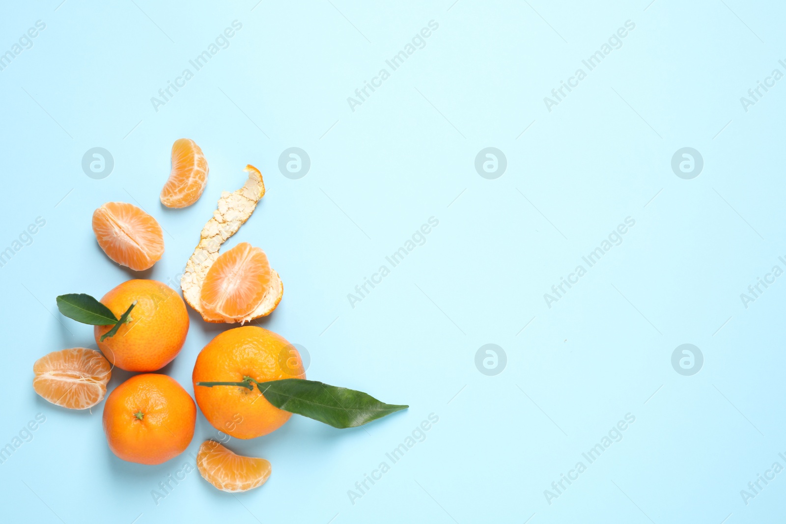 Photo of Flat lay composition with fresh ripe tangerines and leaves on light blue background, space for text. Citrus fruit