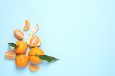 Flat lay composition with fresh ripe tangerines and leaves on light blue background, space for text. Citrus fruit