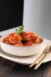 Photo of Delicious stuffed cabbage rolls cooked with tomato sauce on wooden table, closeup. Space for text