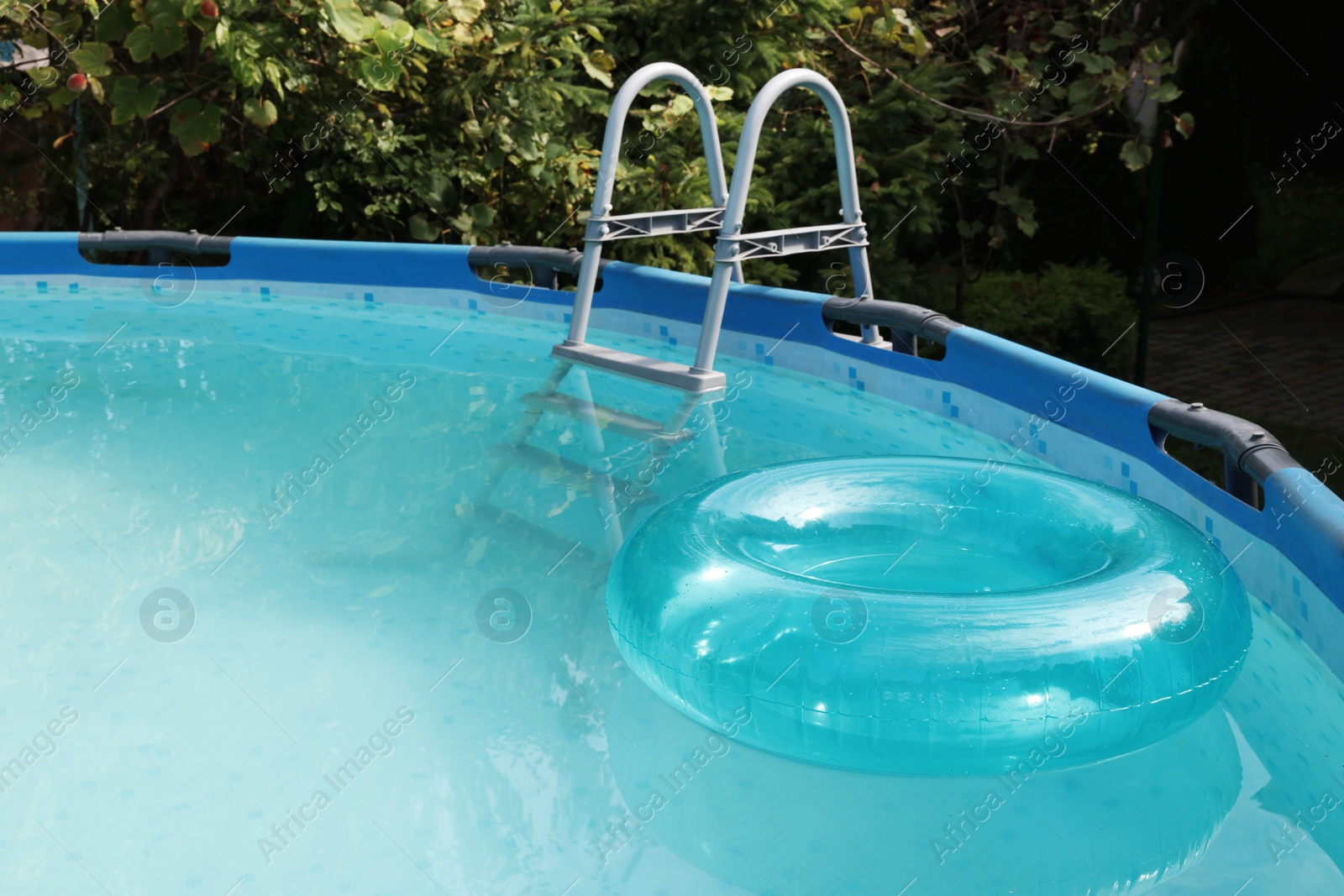 Photo of Inflatable ring floating on water in above ground swimming pool outdoors