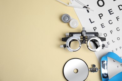 Different ophthalmologist tools on beige background, flat lay. Space for text