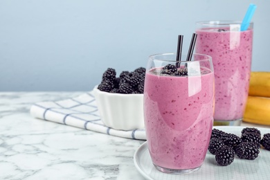 Delicious blackberry smoothie in glasses on marble table. Space for text