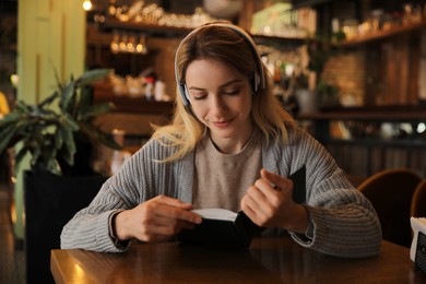 Photo of Woman listening to audiobook at table in cafe