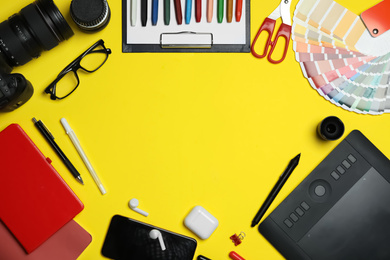 Photo of Flat lay composition with graphic drawing tablet and different office items on yellow background, space for text. Designer's workplace