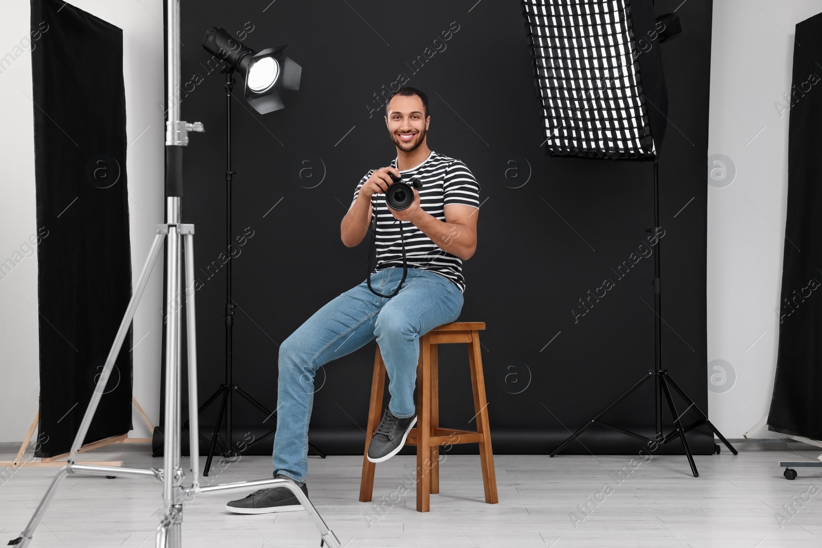 Photo of Young professional photographer with camera in modern photo studio