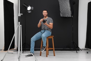 Photo of Young professional photographer with camera in modern photo studio