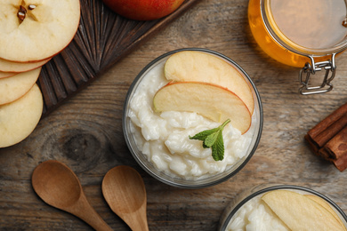 Delicious rice pudding with apple on wooden table, flat lay