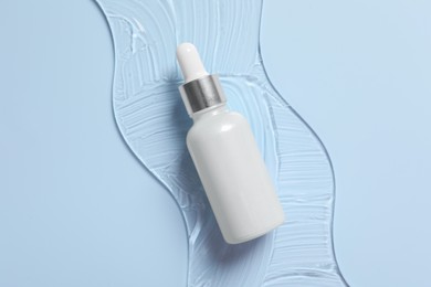 Bottle of cosmetic serum on light blue background, top view