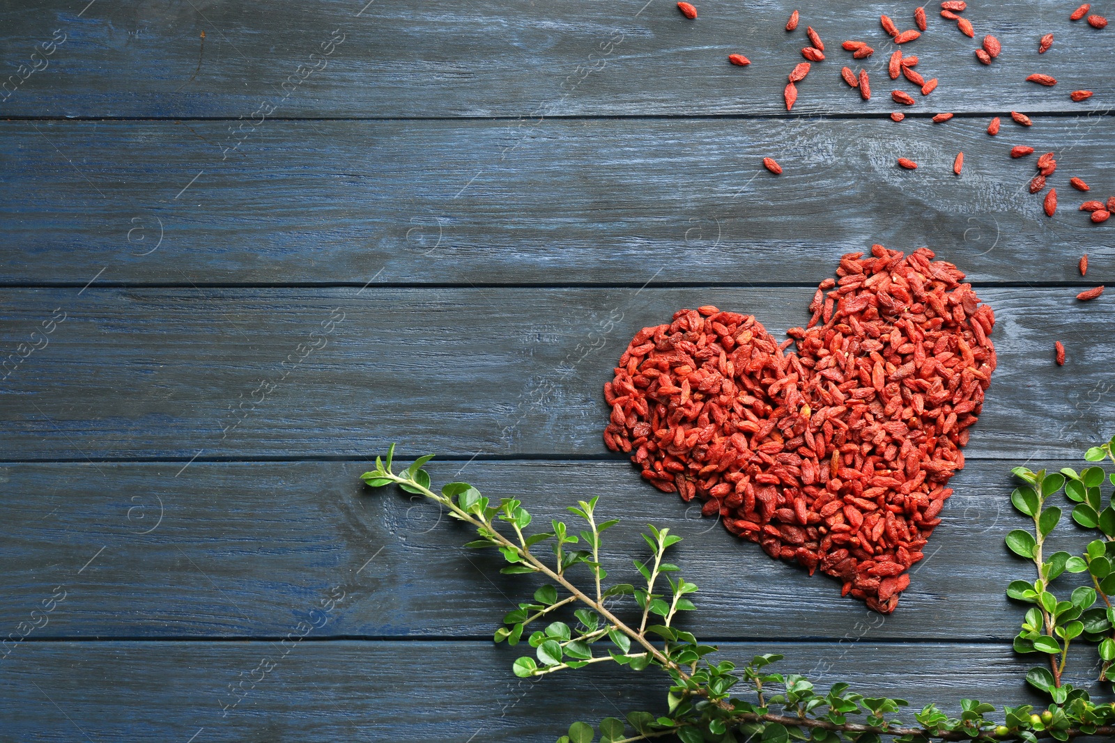 Photo of Heart made of dried goji berries on blue wooden table, top view with space for text. Healthy superfood