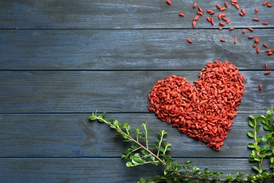 Heart made of dried goji berries on blue wooden table, top view with space for text. Healthy superfood