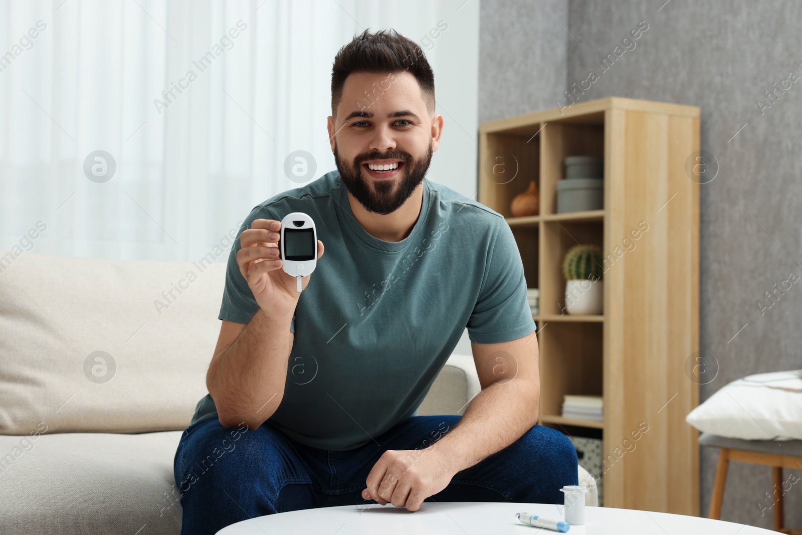 Photo of Diabetes test. Smiling man showing glucometer at home