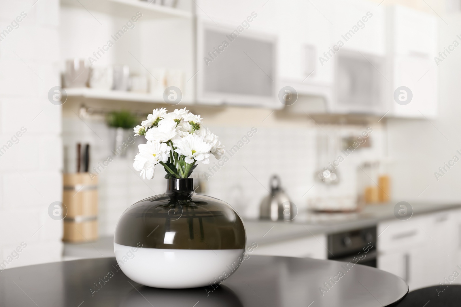 Photo of Vase with beautiful flowers on table in kitchen interior. Space for text