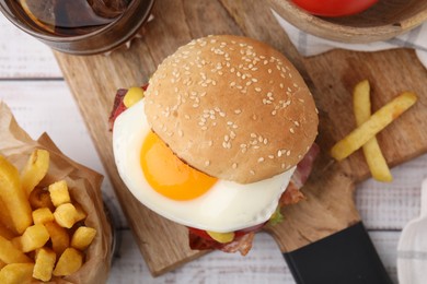 Photo of Delicious burger with fried egg, french fries and soda drink served on white wooden table, flat lay