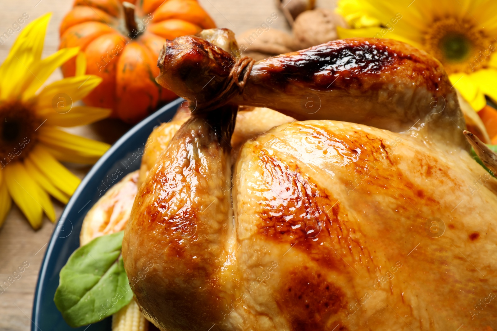 Photo of Traditional cooked turkey and autumn decor on wooden table, closeup Thanksgiving day celebration