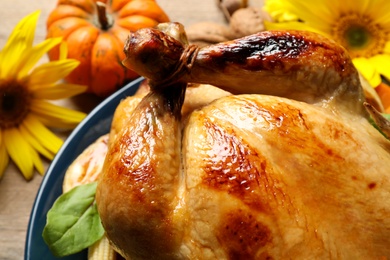 Photo of Traditional cooked turkey and autumn decor on wooden table, closeup Thanksgiving day celebration