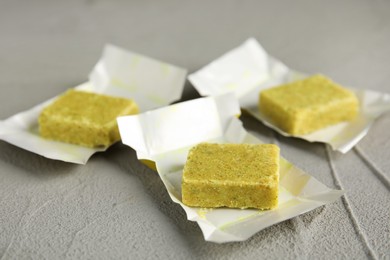Photo of Bouillon cubes with wraps on light grey table, closeup