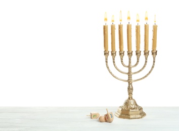Photo of Golden menorah and Hanukkah dreidels with He, Gimel, Nun symbols on white background