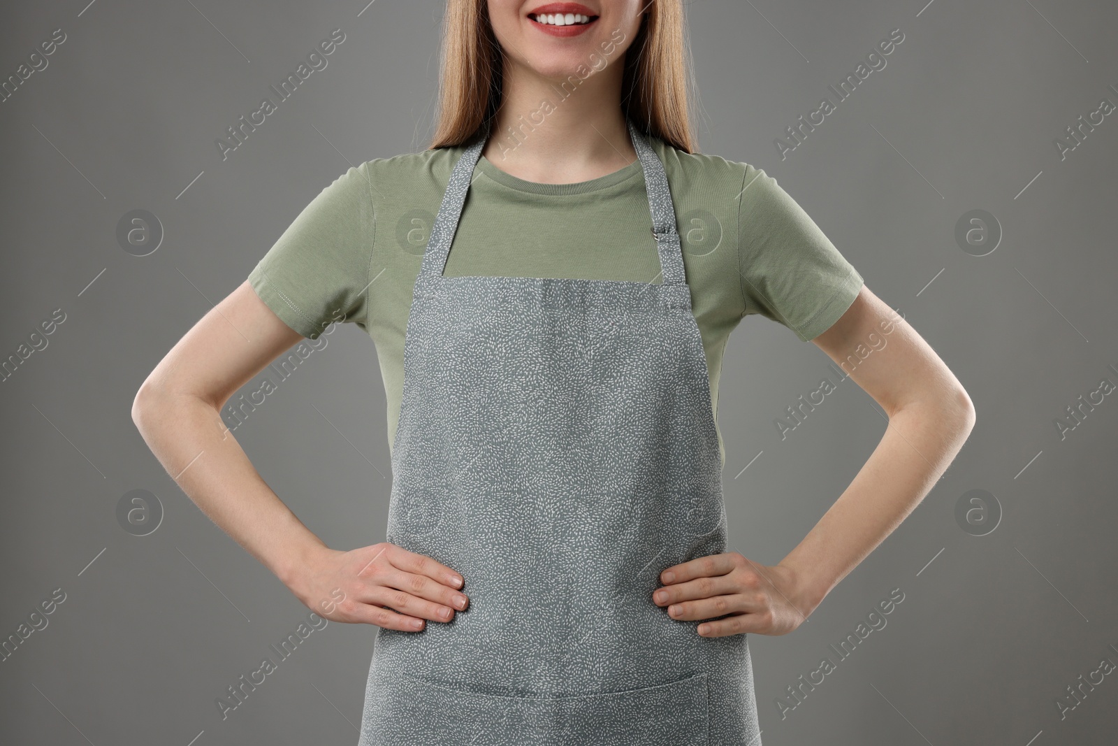 Photo of Woman wearing kitchen apron on grey background, closeup. Mockup for design