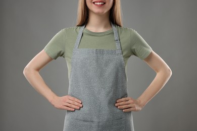 Woman wearing kitchen apron on grey background, closeup. Mockup for design