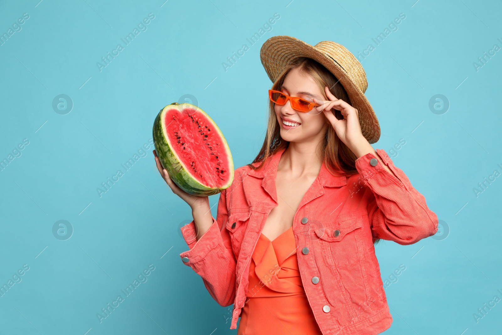 Photo of Beautiful girl with half of watermelon on light blue background