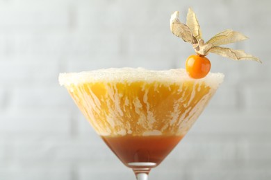 Delicious cocktail decorated with physalis fruit on blurred background, closeup