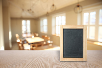 Image of Blank small blackboard on wooden table in cafe, mockup for menu design 