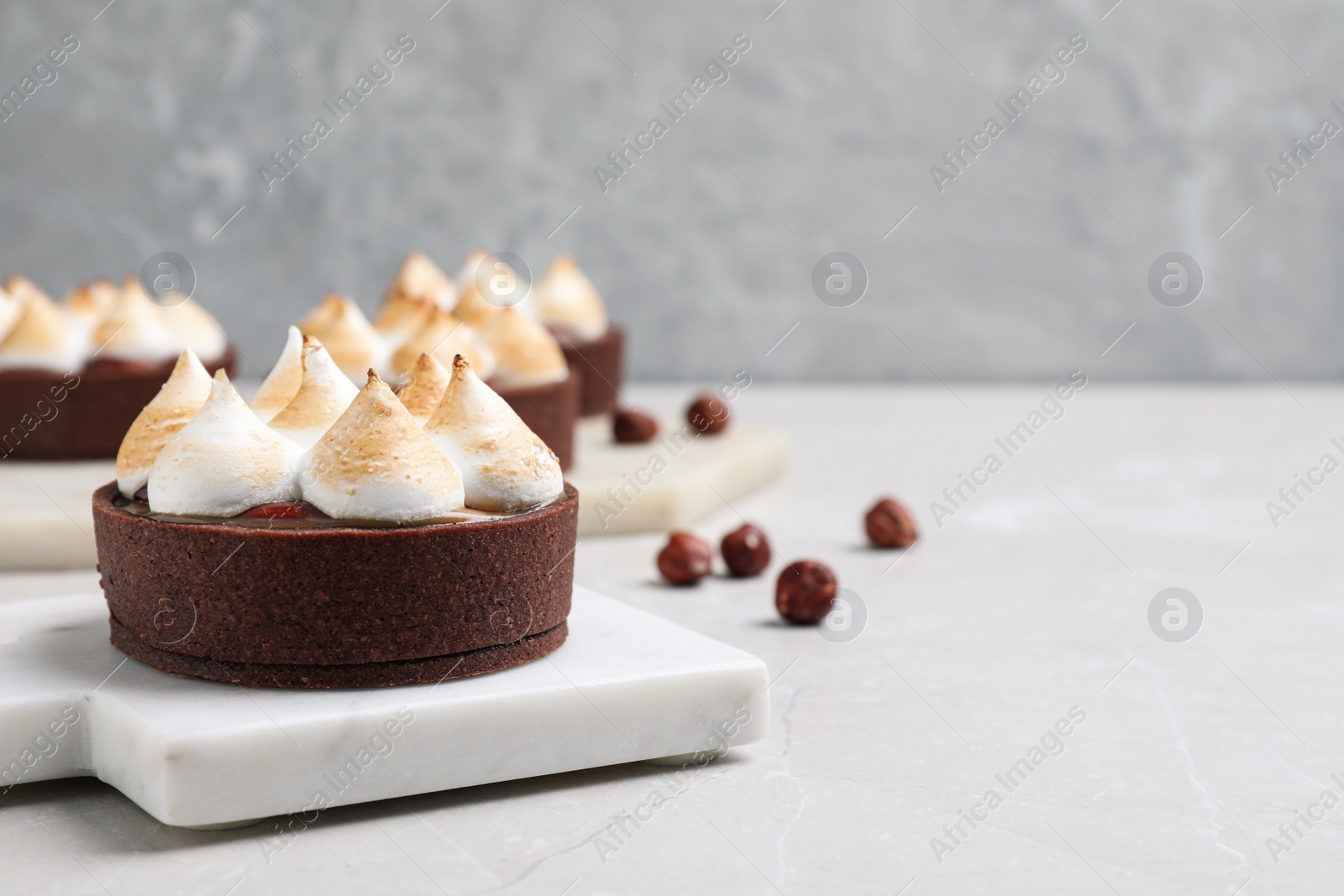 Photo of Delicious salted caramel chocolate tart with meringue on light grey table. Space for text