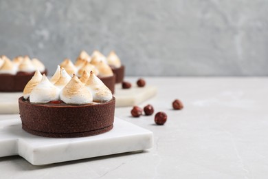 Photo of Delicious salted caramel chocolate tart with meringue on light grey table. Space for text