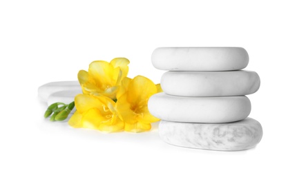 Stack of spa stones and freesia flowers on white background