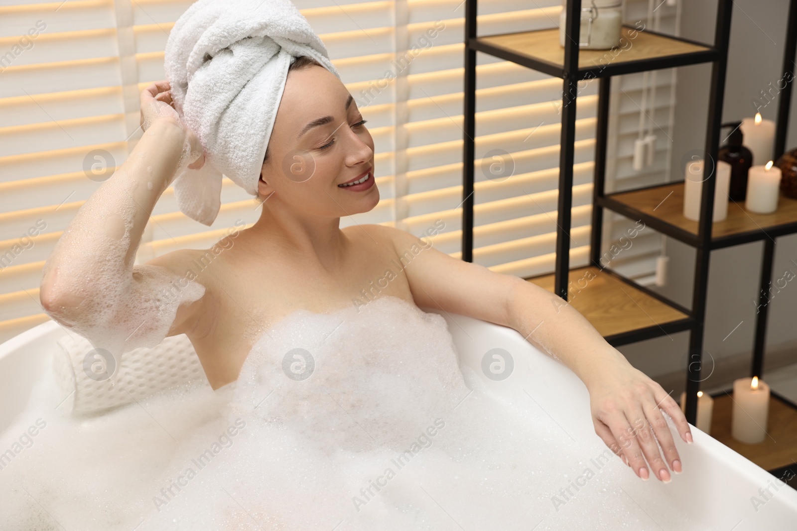 Photo of Happy woman taking bath with foam in tub indoors