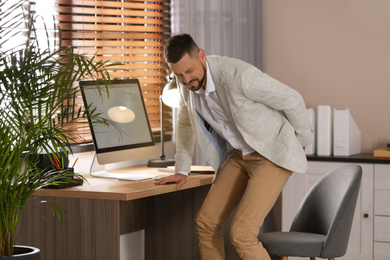 Photo of Man suffering from hemorrhoid at workplace in office