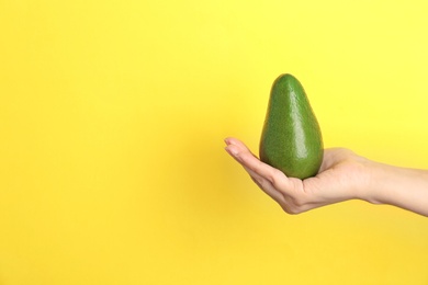 Photo of Woman holding ripe avocado on color background