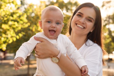 Photo of Portrait of young mother with her cute baby in park on sunny day