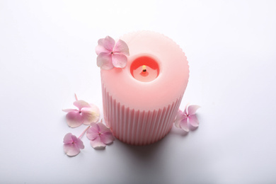 Photo of Burning pink wax candle and flowers isolated on white, above view