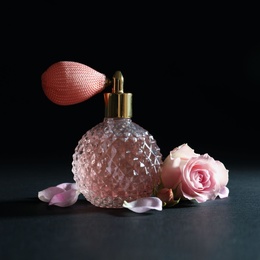 Vintage bottle of perfume and beautiful flower on black background