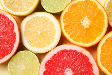 Photo of Different cut citrus fruits on beige table, flat lay