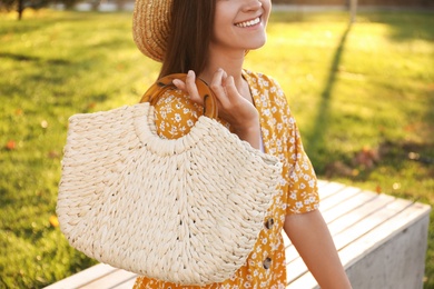 Young woman with stylish straw bag in park, closeup