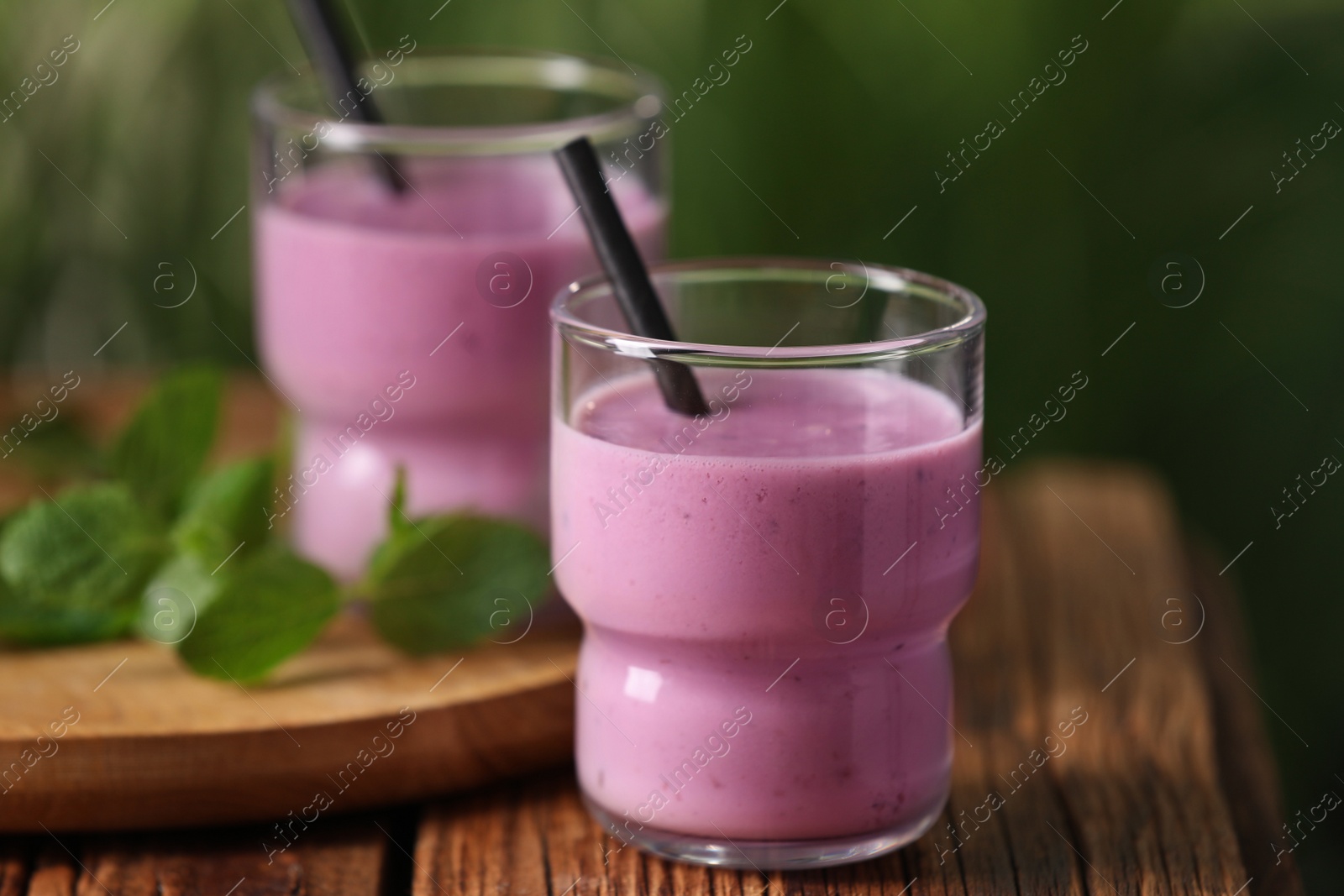 Photo of Delicious blackberry smoothie in glasses on wooden table, closeup