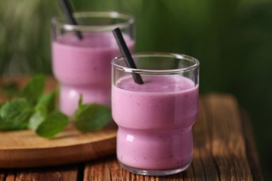 Photo of Delicious blackberry smoothie in glasses on wooden table, closeup