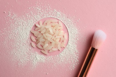 Loose face powder, rice and makeup brush on pink background, flat lay