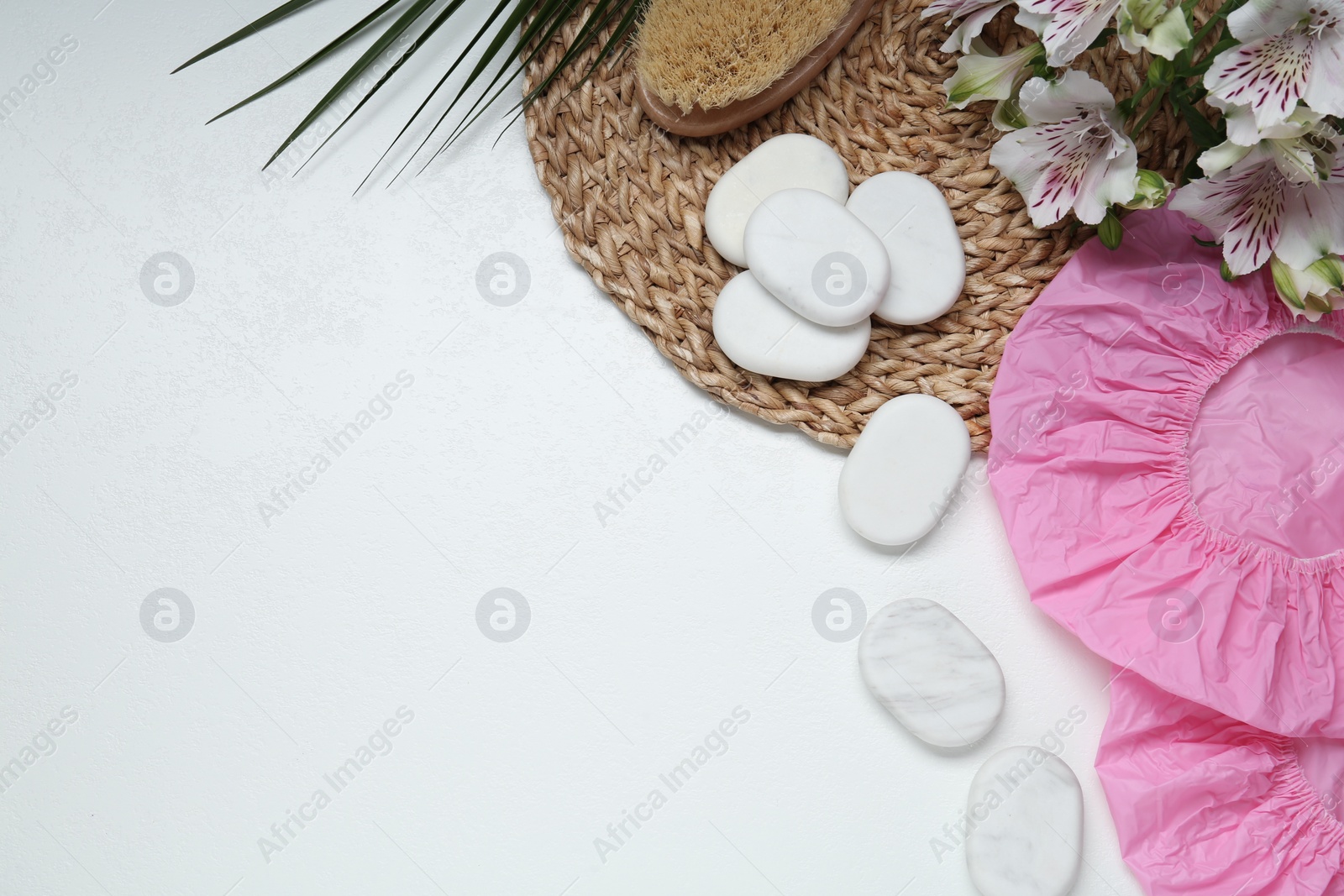 Photo of Flat lay composition with shower caps and spa stones on white wooden background. Space for text