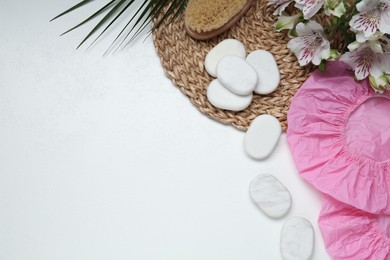 Photo of Flat lay composition with shower caps and spa stones on white wooden background. Space for text
