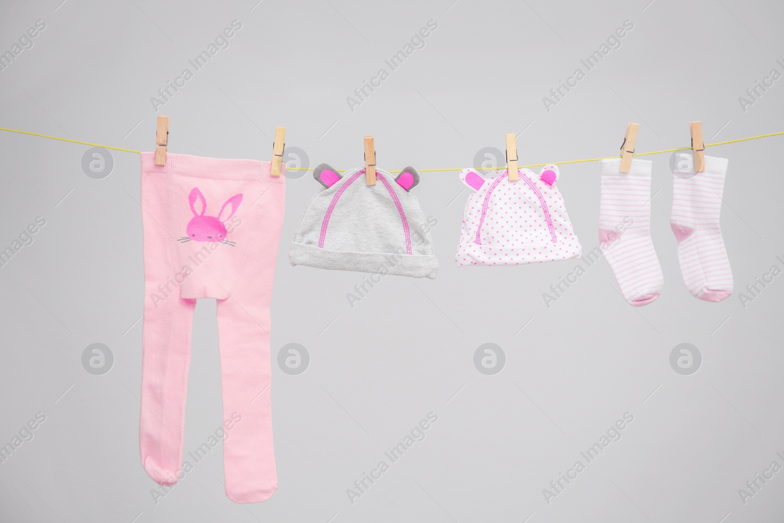 Photo of Baby clothes hanging on washing line against gray background