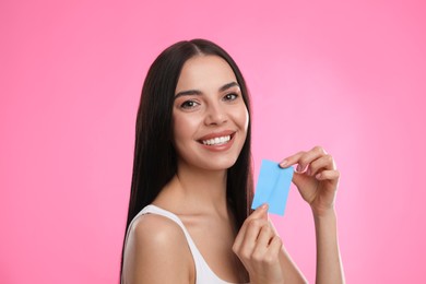 Beautiful woman with mattifying wipe on pink background