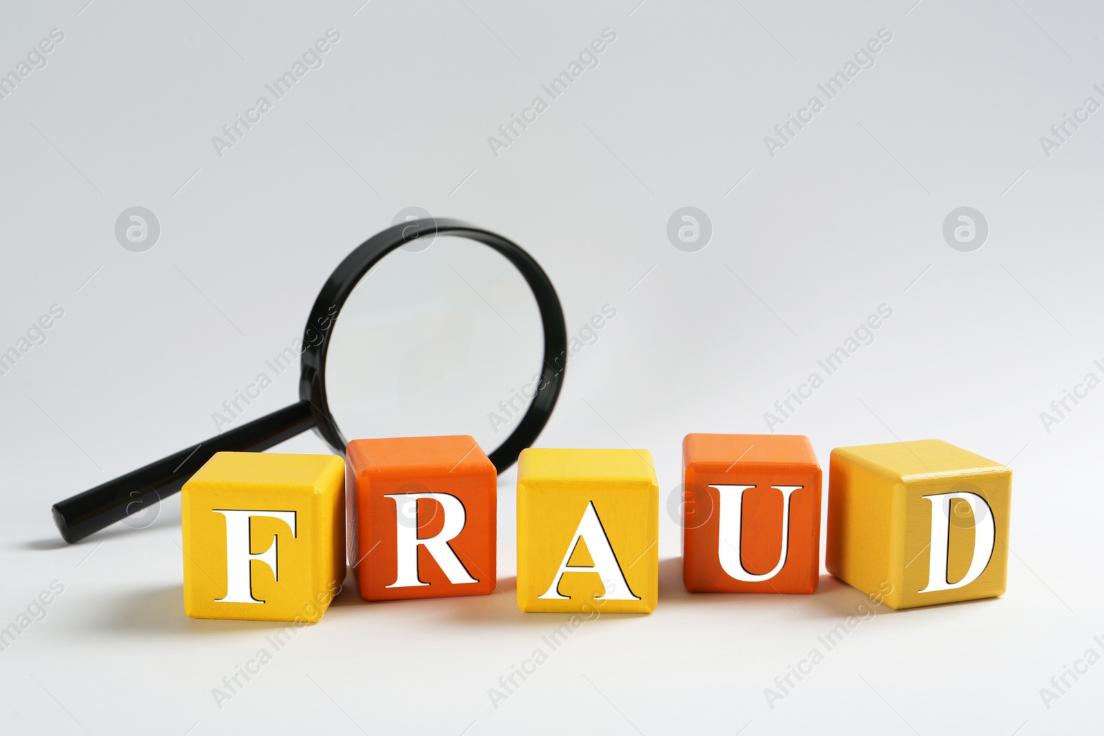 Photo of Wooden cubes with word Fraud and magnifying glass on light background. Space for text