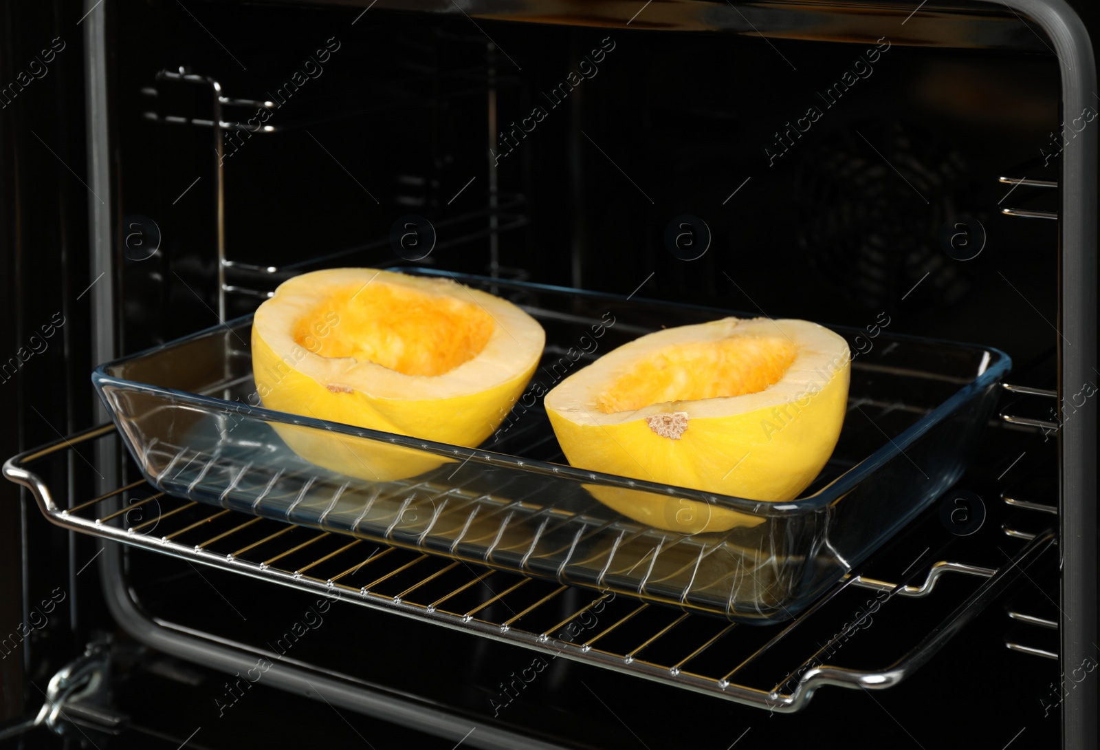 Photo of Baking dish with halves of fresh spaghetti squash in oven