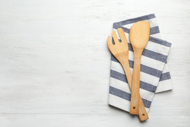 Photo of Different kitchen utensils and napkin on wooden background, top view with space for text