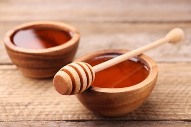 Photo of Delicious honey in bowls and dipper on wooden table