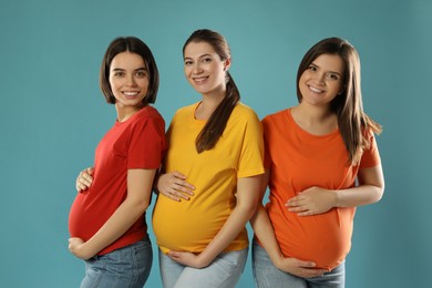 Happy young pregnant women on turquoise background