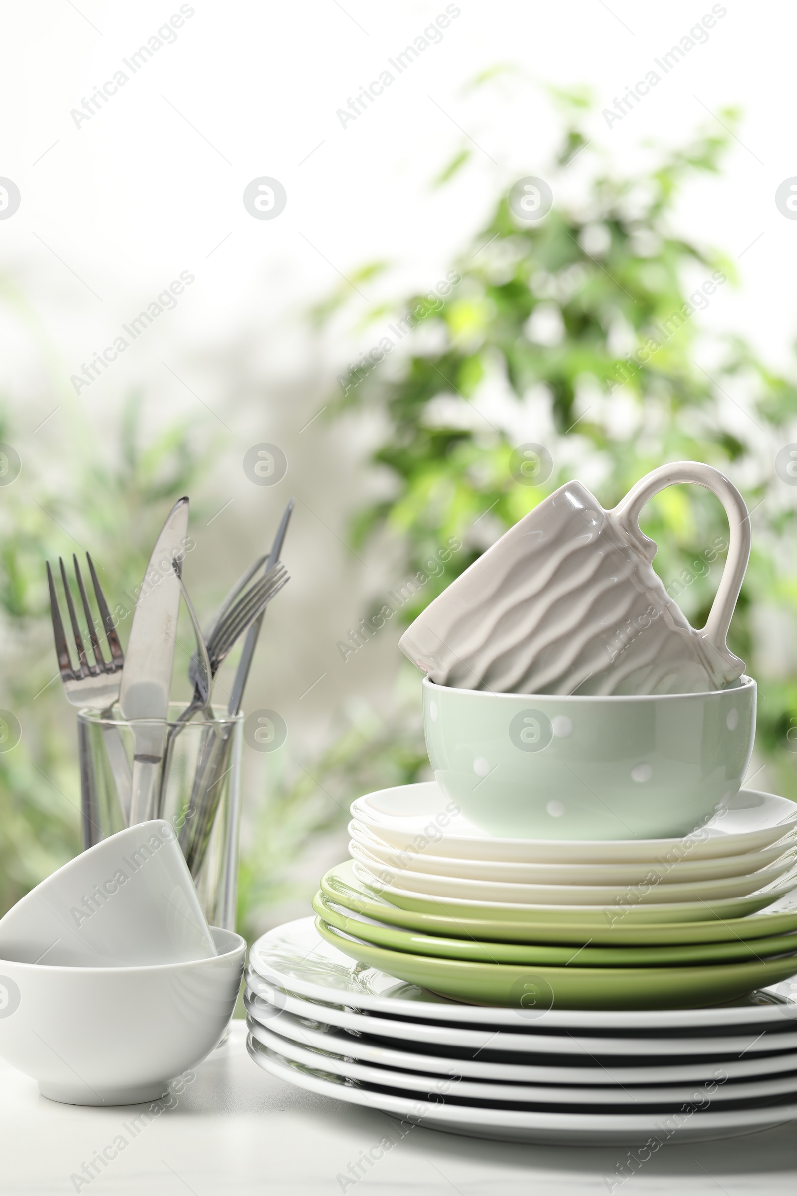 Photo of Beautiful ceramic dishware, cutlery and cup on white table outdoors